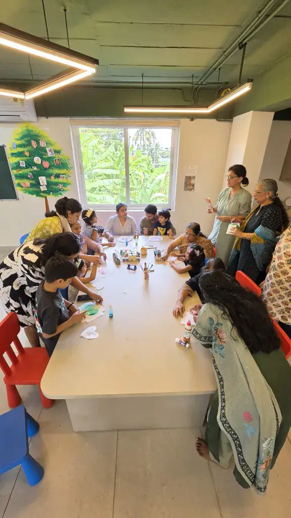Children, parents and teachers making crafts together around a table at ULTRA_school