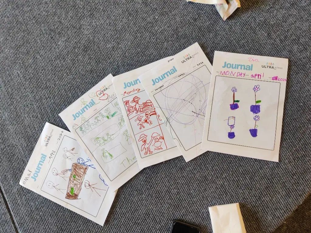 Children's ULTRA_school learning journals with their drawings and daily entries