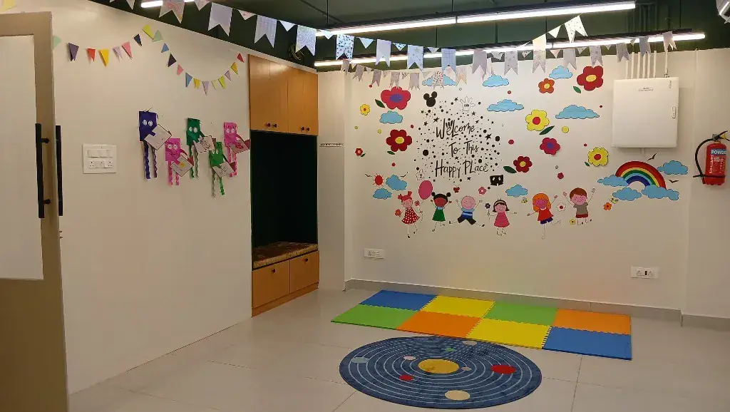 ULTRA_school play corner with soft foam mats, a solar-system rug and a Welcome To This Happy Place mural