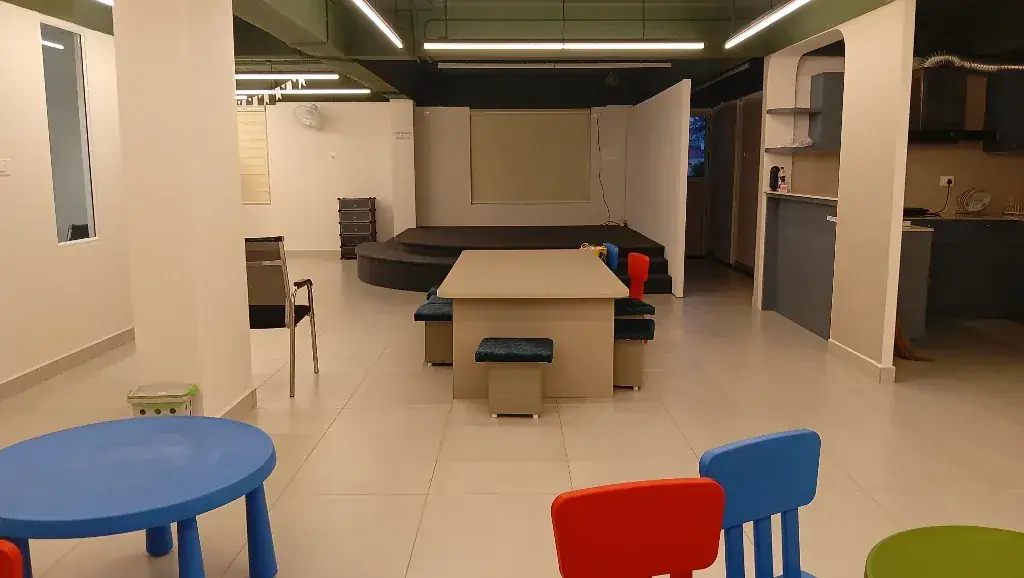 Open studio space with flexible tables and a stage at ULTRA_school Kochi